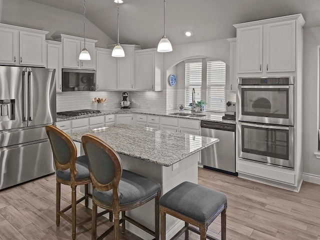 kitchen featuring white cabinetry, a center island, sink, stainless steel appliances, and pendant lighting