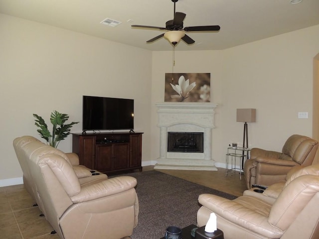 living room with ceiling fan, visible vents, a fireplace with raised hearth, and baseboards