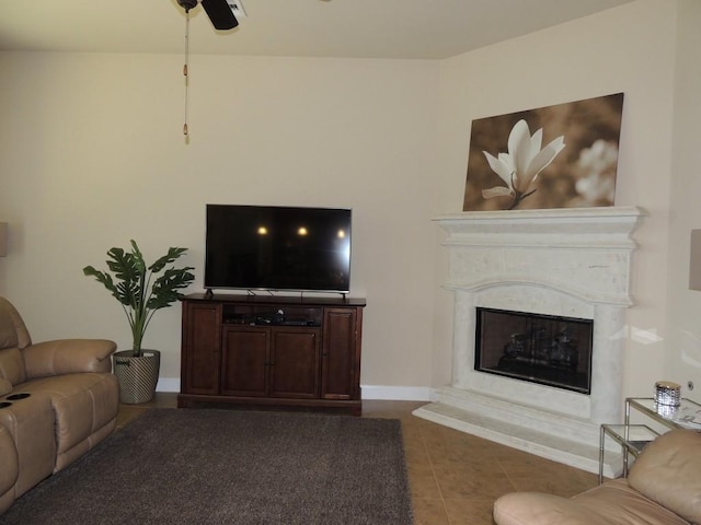 tiled living room with ceiling fan, baseboards, and a premium fireplace