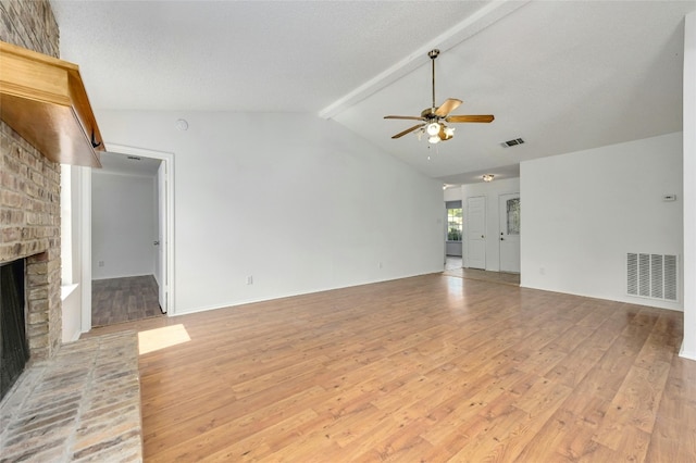 unfurnished living room with lofted ceiling with beams, light wood-style floors, a fireplace, and visible vents