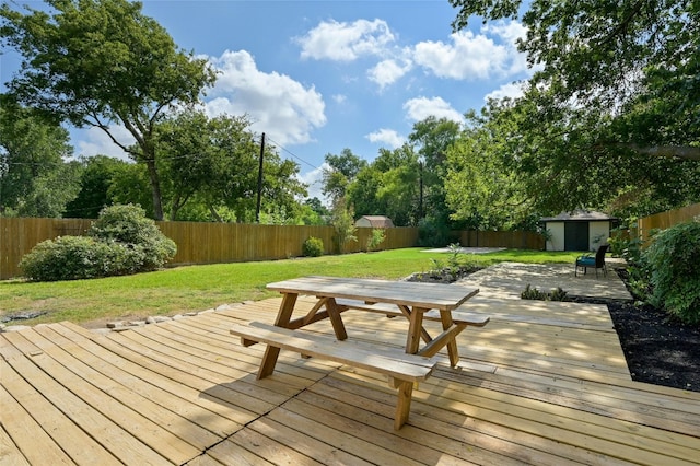 deck featuring a yard, a fenced backyard, an outdoor structure, and a shed