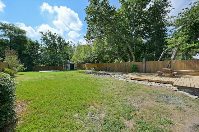 view of yard with a fenced backyard, a shed, an outbuilding, and a wooden deck