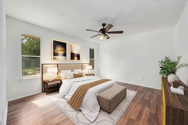 bedroom with ceiling fan, hardwood / wood-style floors, and a textured ceiling