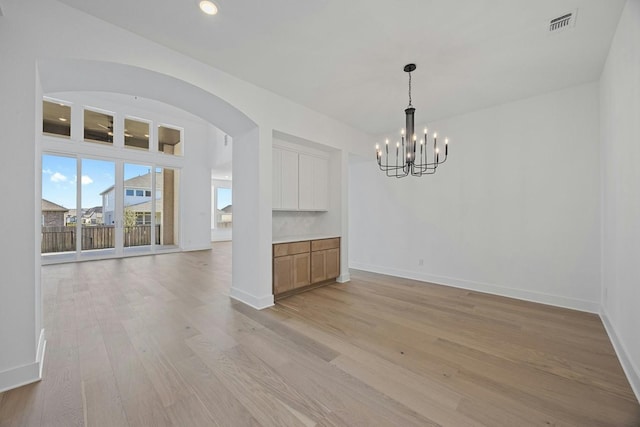 spare room featuring a notable chandelier and light hardwood / wood-style floors