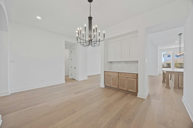 unfurnished dining area with an inviting chandelier and light hardwood / wood-style flooring