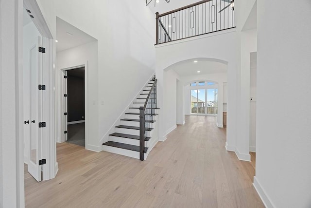 foyer entrance with light hardwood / wood-style floors and a towering ceiling