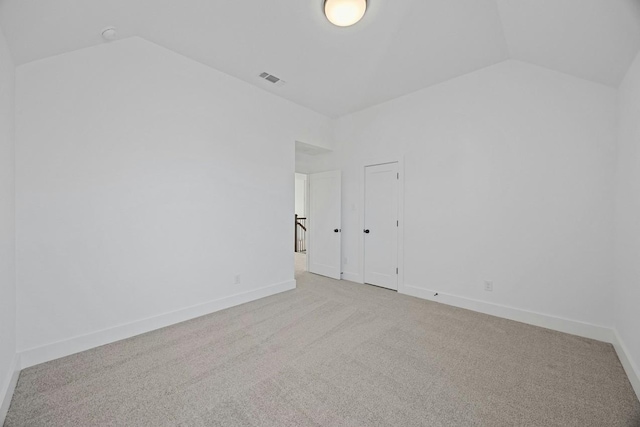 carpeted empty room featuring vaulted ceiling