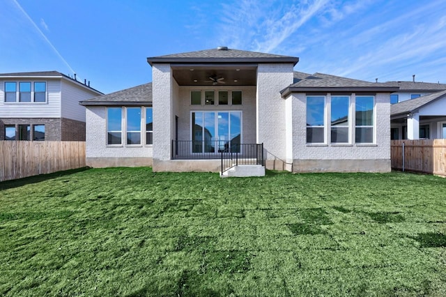 back of property with ceiling fan and a yard