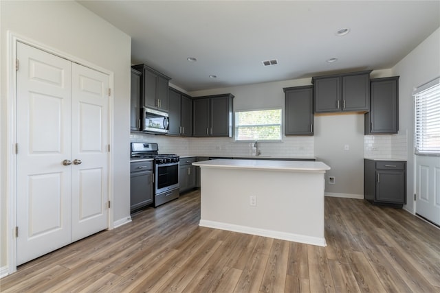 kitchen with gray cabinetry, stainless steel appliances, wood-type flooring, and a center island