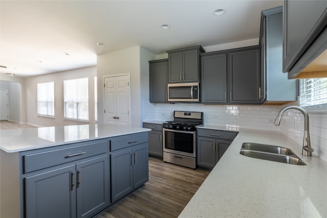 kitchen featuring tasteful backsplash, stainless steel appliances, light stone counters, sink, and dark hardwood / wood-style floors