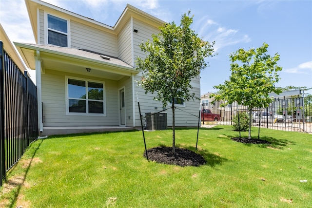 rear view of property with a yard and central air condition unit