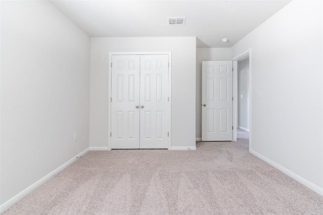 unfurnished bedroom with a closet and light colored carpet