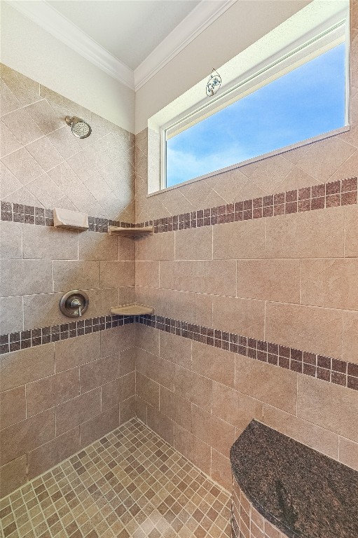 bathroom with tiled shower and crown molding