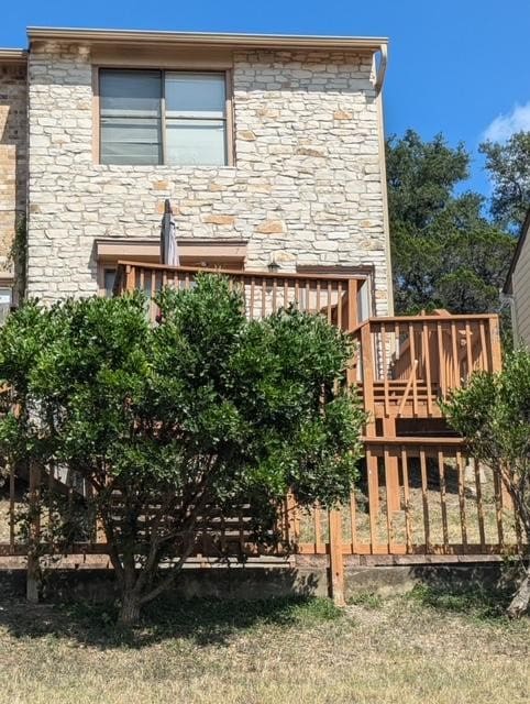 back of property with a deck and stone siding