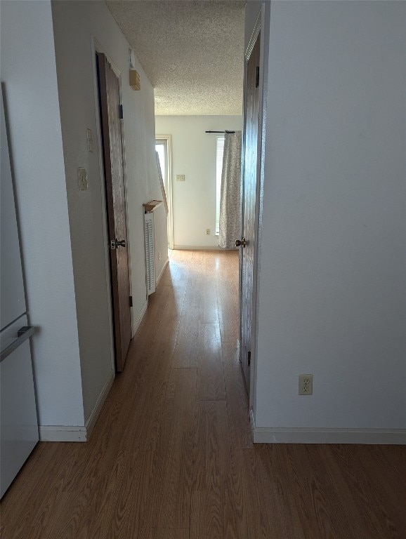 hallway featuring hardwood / wood-style flooring and a textured ceiling