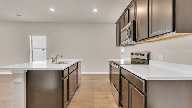 kitchen with a center island with sink, light hardwood / wood-style flooring, appliances with stainless steel finishes, and sink