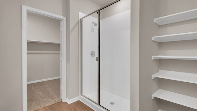 bathroom with a shower with door and wood-type flooring