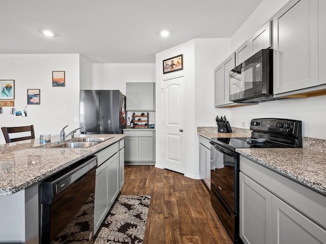 19104 Romano Dr, Elgin, TX 78621 - kitchen with black appliances, a sink, dark wood-style flooring, light stone countertops, and gray cabinetry