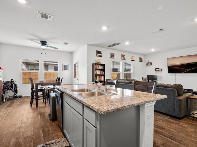 kitchen featuring a sink, open floor plan, dark wood-style floors, a center island with sink, and dishwasher