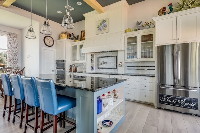 kitchen featuring dark stone countertops, decorative backsplash, appliances with stainless steel finishes, light hardwood / wood-style flooring, and decorative light fixtures