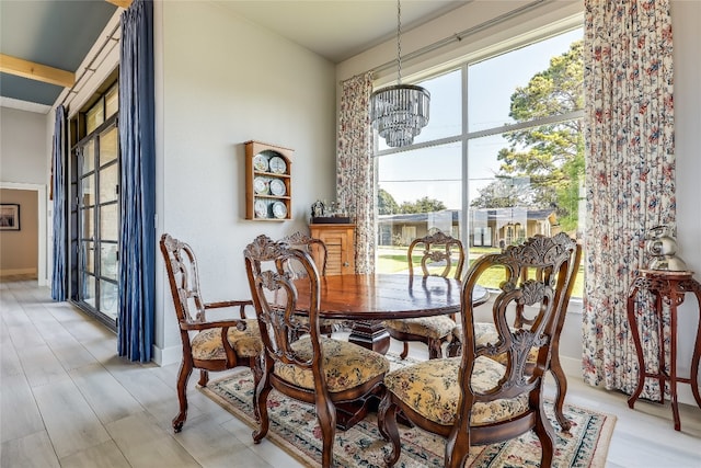 dining area with light hardwood / wood-style flooring, a wealth of natural light, and an inviting chandelier