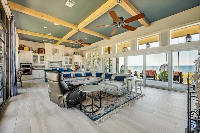 living room with beamed ceiling, ceiling fan, a water view, and light hardwood / wood-style floors