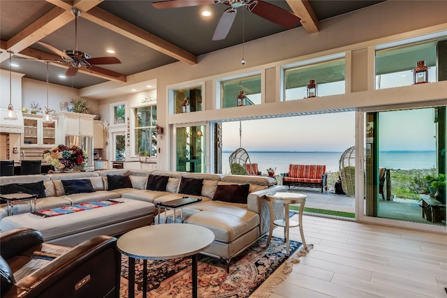 living room featuring ceiling fan, a high ceiling, a water view, light hardwood / wood-style flooring, and beamed ceiling