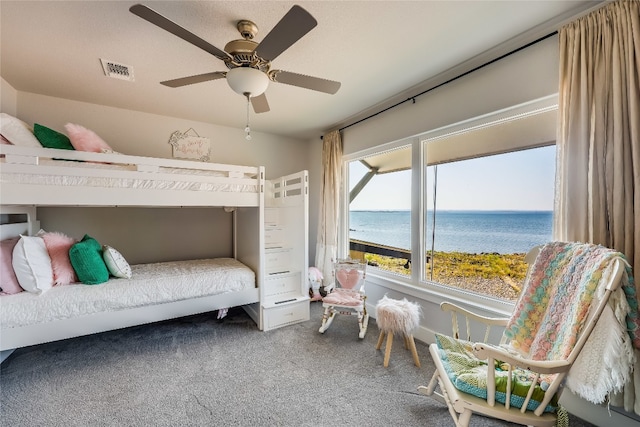 bedroom featuring carpet, ceiling fan, multiple windows, and a water view