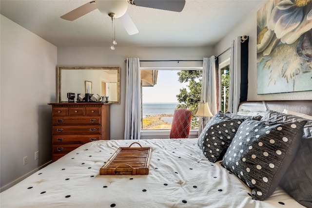 bedroom with ceiling fan and a water view