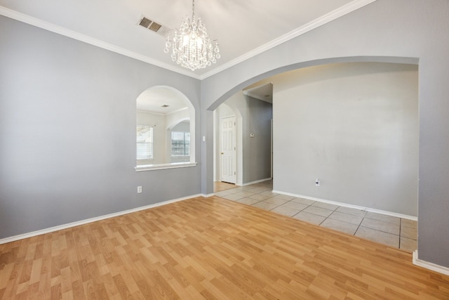 tiled empty room featuring ornamental molding and an inviting chandelier