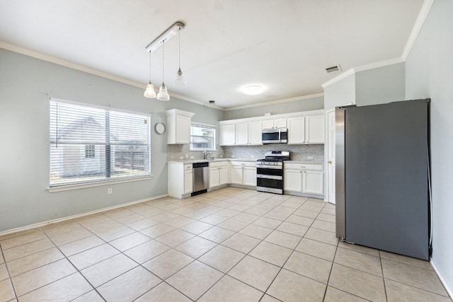 kitchen with light tile patterned flooring, stainless steel appliances, ornamental molding, and white cabinetry