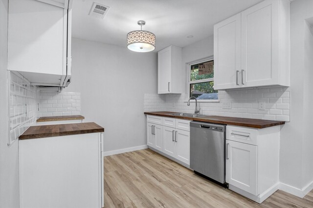 kitchen with wood counters, white cabinets, dishwasher, and sink