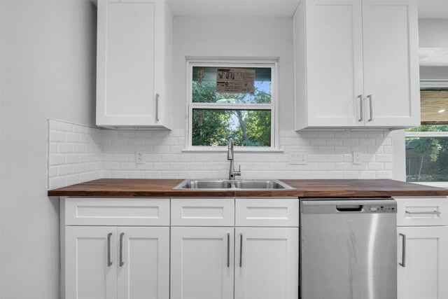 kitchen with wooden counters, decorative backsplash, stainless steel dishwasher, sink, and white cabinets