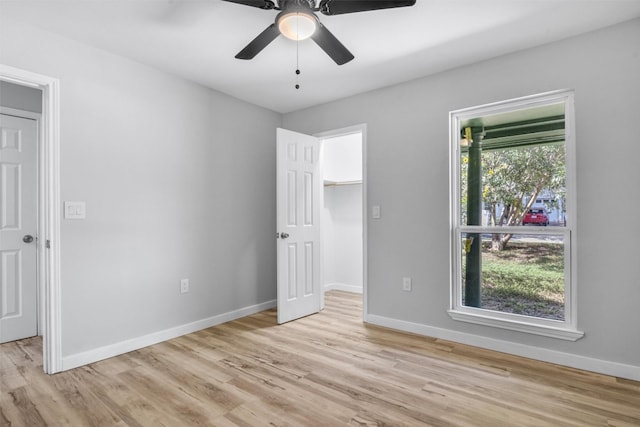 unfurnished bedroom featuring ceiling fan, light hardwood / wood-style floors, and a spacious closet