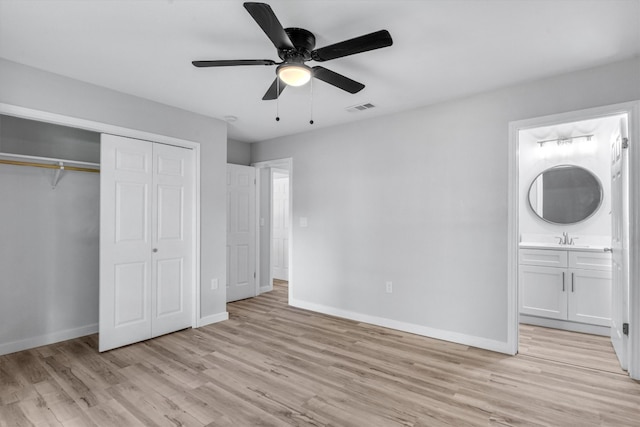 unfurnished bedroom with light hardwood / wood-style flooring, a closet, connected bathroom, ceiling fan, and sink