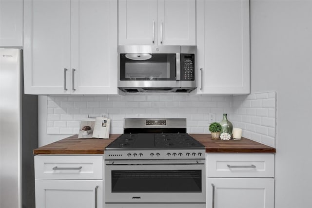 kitchen with wooden counters, appliances with stainless steel finishes, backsplash, and white cabinetry