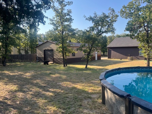 view of yard with a fenced in pool, a shed, and central AC unit