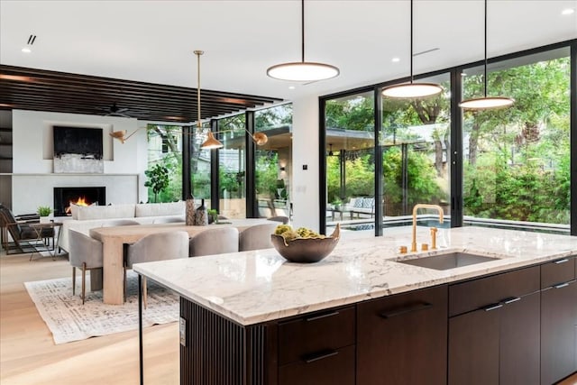 kitchen with dark brown cabinets, sink, expansive windows, and decorative light fixtures