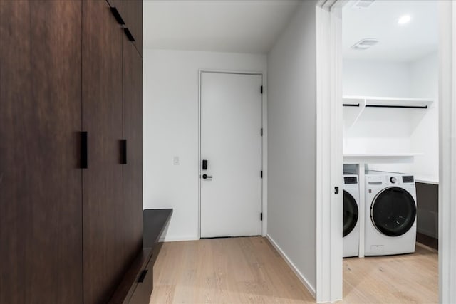 laundry room featuring washing machine and dryer and light hardwood / wood-style flooring