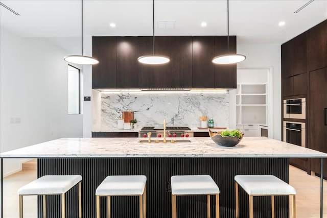 kitchen featuring a kitchen bar, pendant lighting, backsplash, and sink