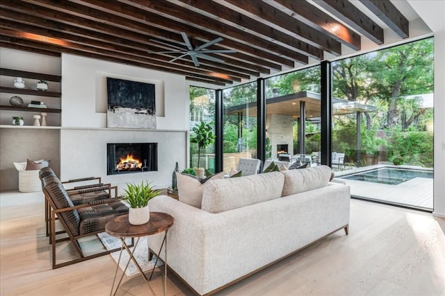 living room with a wall of windows, wood finished floors, and a warm lit fireplace