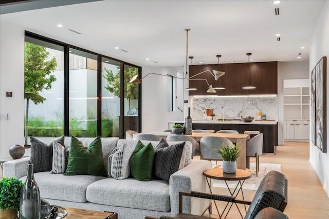 living area with expansive windows, light wood finished floors, and recessed lighting
