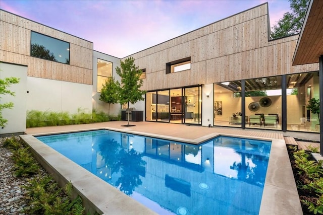 pool at dusk featuring a patio