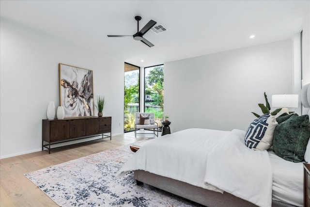 bedroom featuring light wood-type flooring, expansive windows, and ceiling fan