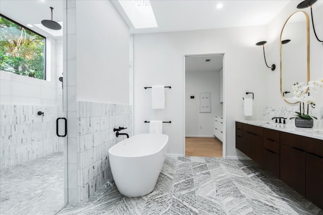 bathroom featuring vanity, separate shower and tub, tile walls, and a skylight