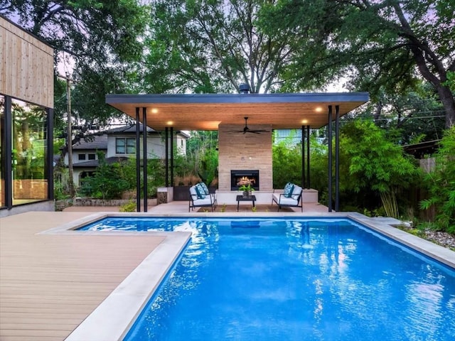 view of swimming pool featuring an outdoor living space with a fireplace, ceiling fan, and a patio area