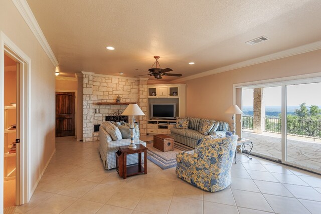 tiled living room with a textured ceiling, a stone fireplace, crown molding, and ceiling fan