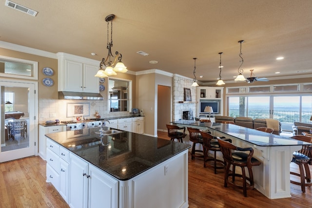 kitchen featuring light wood-type flooring, tasteful backsplash, a kitchen island, and white cabinetry