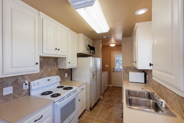 kitchen with white cabinets, white appliances, washing machine and dryer, tasteful backsplash, and sink