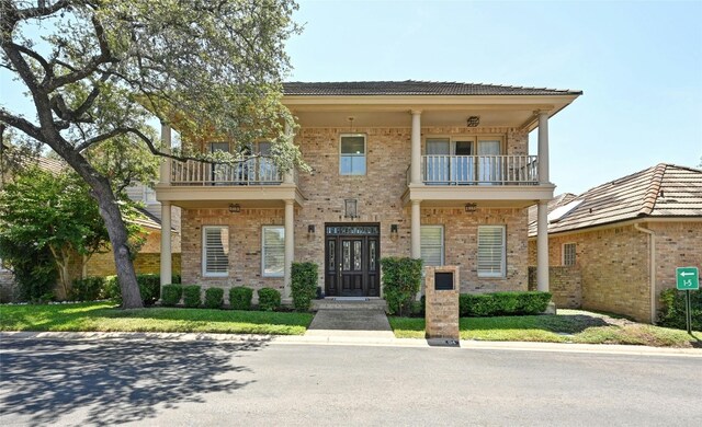 view of front of property featuring a balcony and a front lawn